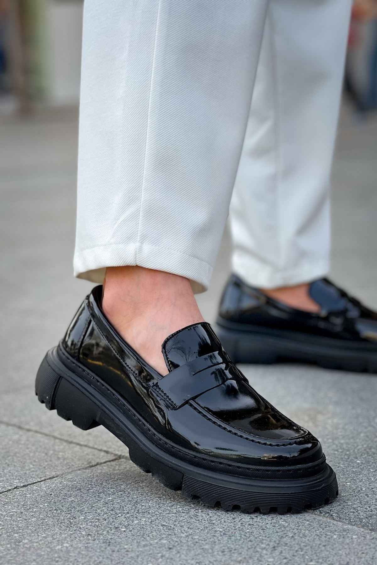 Black patent leather loafer with chunky sole and strap detailing, close side view