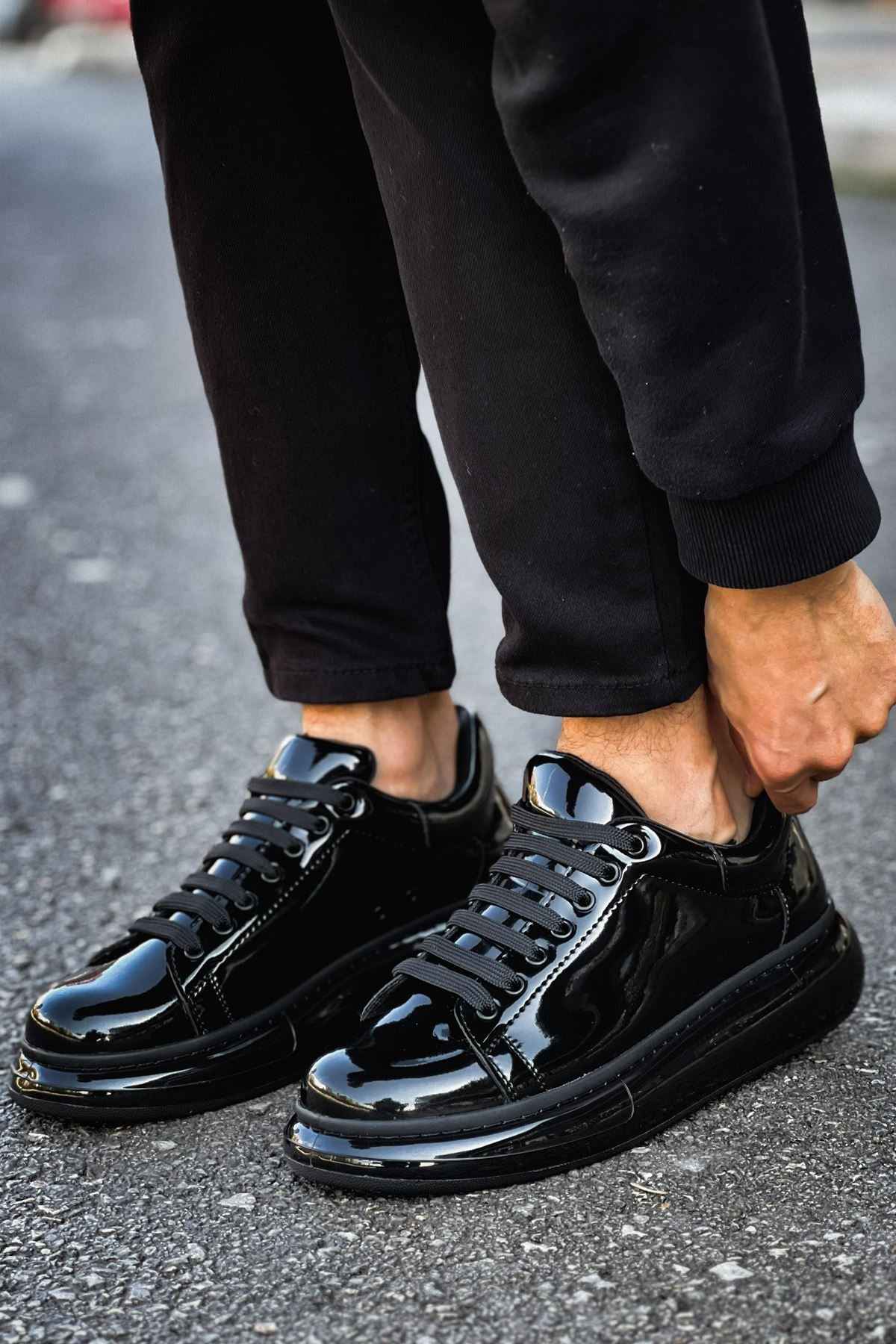 Men's black patent leather sneakers, front-side view with glossy laces and toe