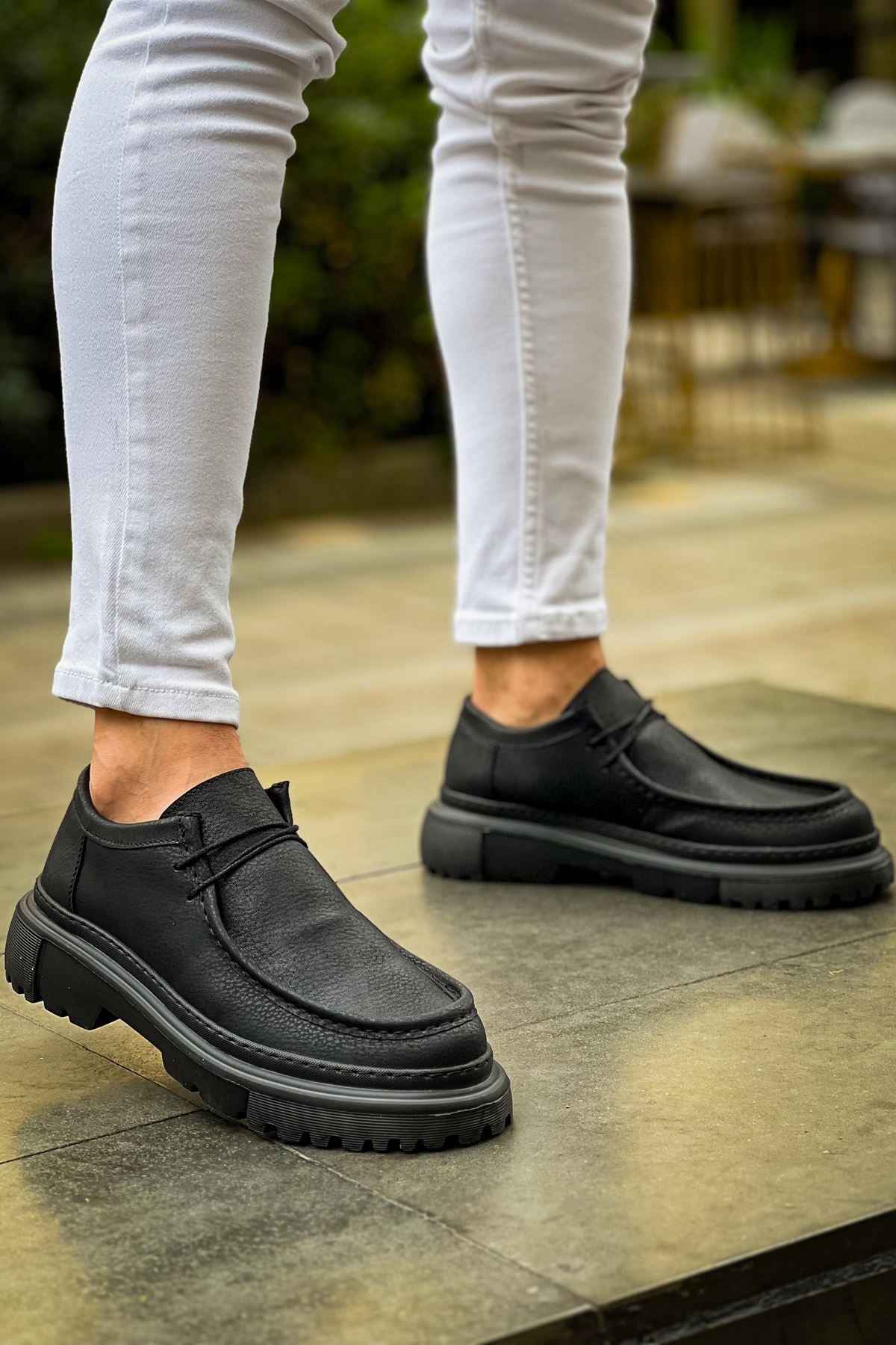 Men's black lace-up shoes with thick tread sole, pair shown on feet