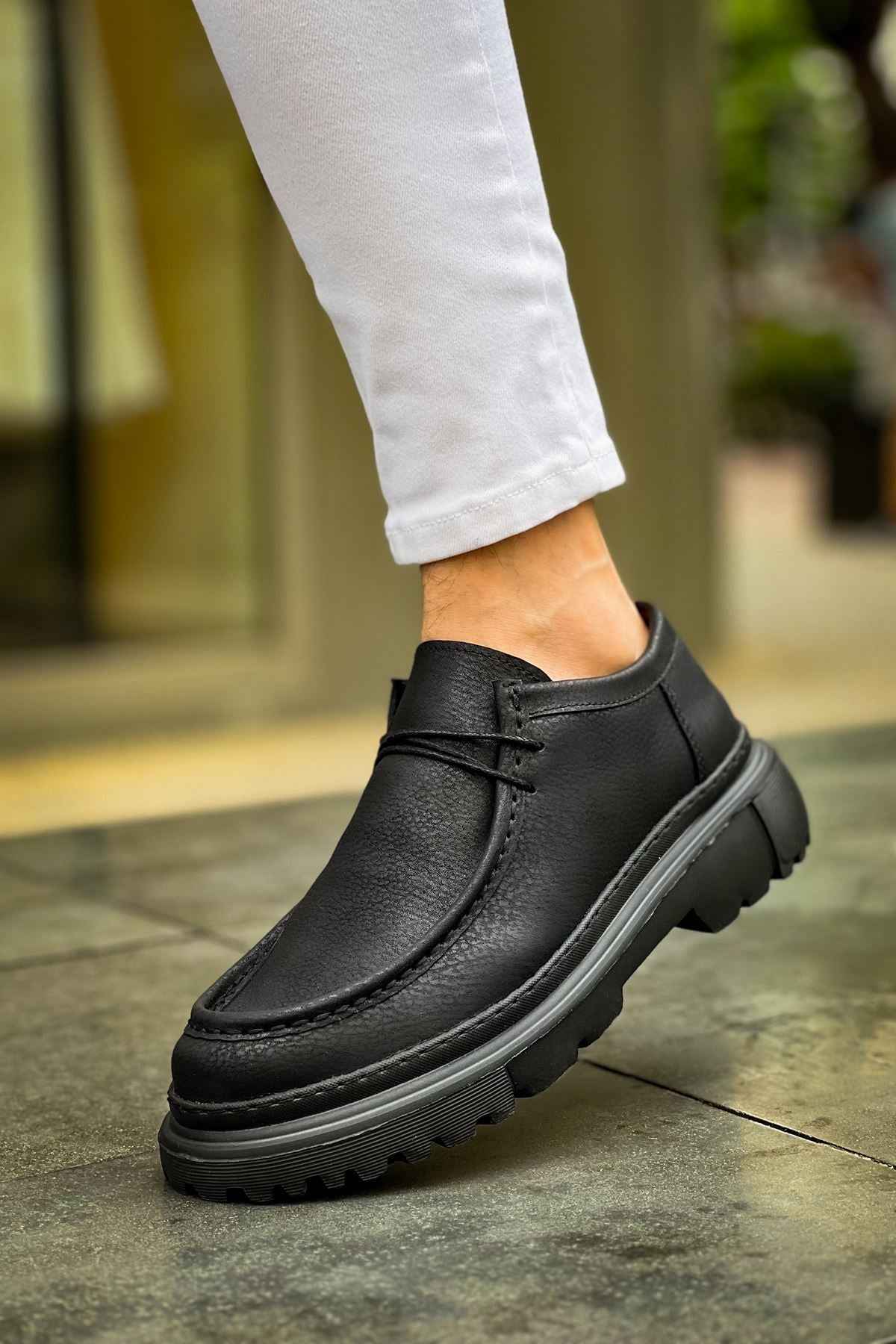 Men's black lace-up shoes with thick tread sole, close-up side view