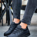 Men's black sneakers, lace-up front and side panels, worn with cuffed jeans