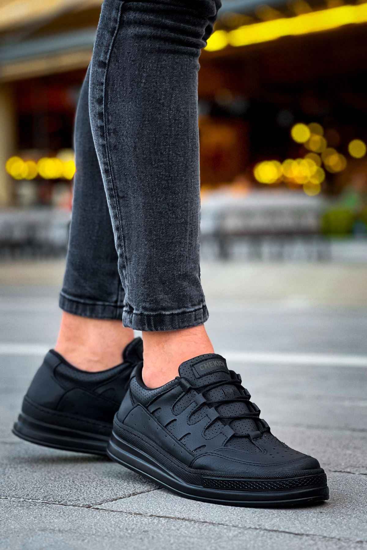 Men's black sneakers with lace-up vamp and textured overlays, side view with jeans