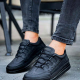 Men's black sneakers with lace-up front and chunky sole, angled view with jeans