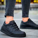 Men's black sneakers with lace-up front and textured upper, close side view on pavement
