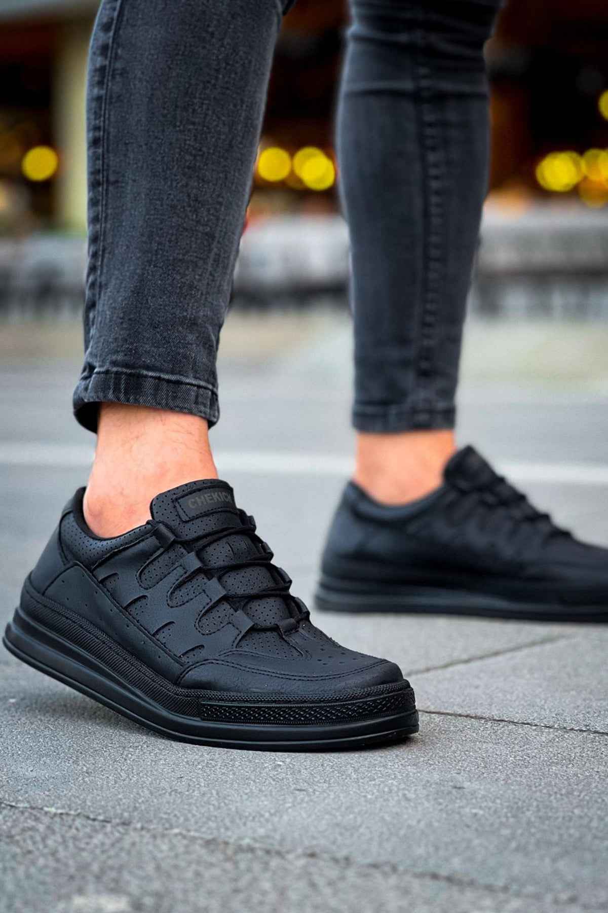 Men's black sneakers with lace-up front and textured upper, close side view on pavement