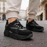 Men's black lace-up sneakers, close side view with textured outsole and gray accents