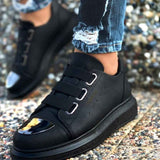 Black sneakers with two hook-and-loop straps, decorative toe patch, and rubber sole