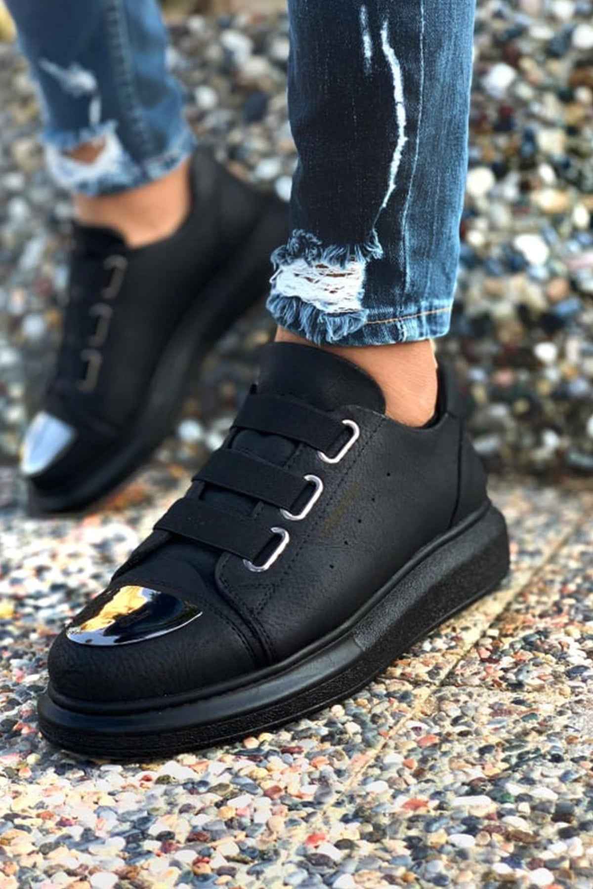 Black sneakers with two hook-and-loop straps, decorative toe patch, and rubber sole