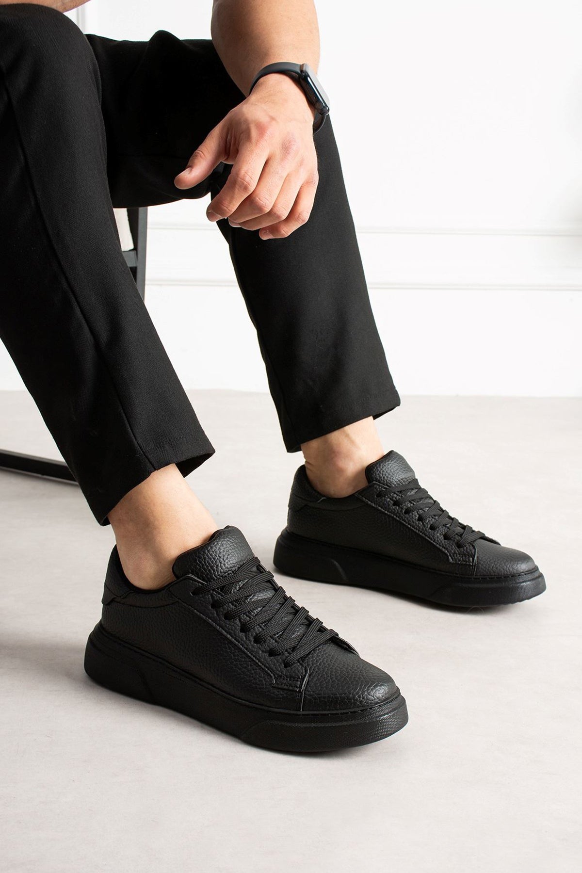Men's black lace-up sneakers, side view with textured upper and rubber sole