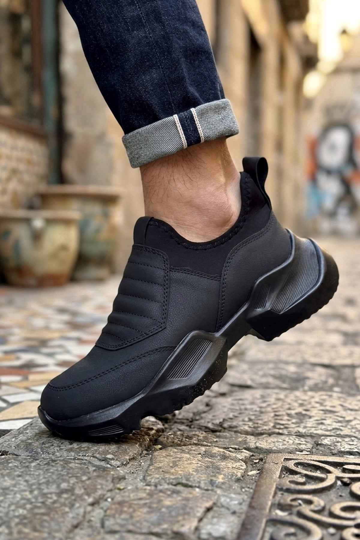 Men's black sneakers with lace-up closure, stitched side panels, and rubber tread sole