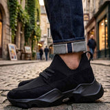 Black lace-up sneakers with textured mesh panels and rubber tread sole