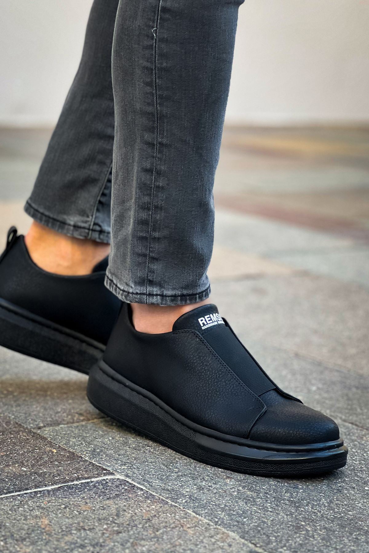 Men's black slip-on sneakers with smooth upper and stitched side, flat rubber sole