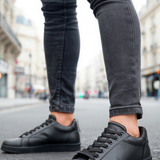 Black lace-up sneakers with padded collar and textured sole tread.
