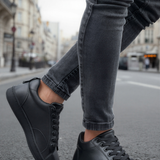 Black lace-up sneakers with smooth toe cap and side stripe paneling.