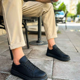 Black lace-up sneakers on feet, low profile with textured upper