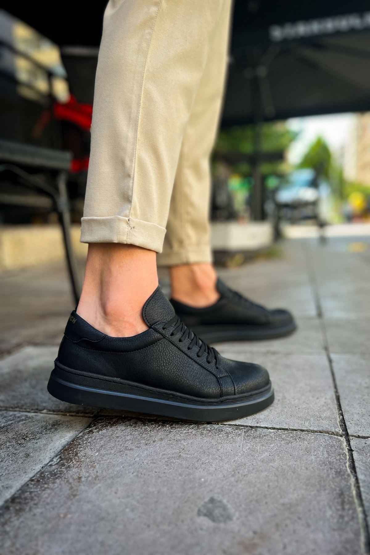 Black lace-up sneakers with textured finish and side stitching detail
