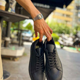 Black lace-up sneakers held together, textured upper with visible laces