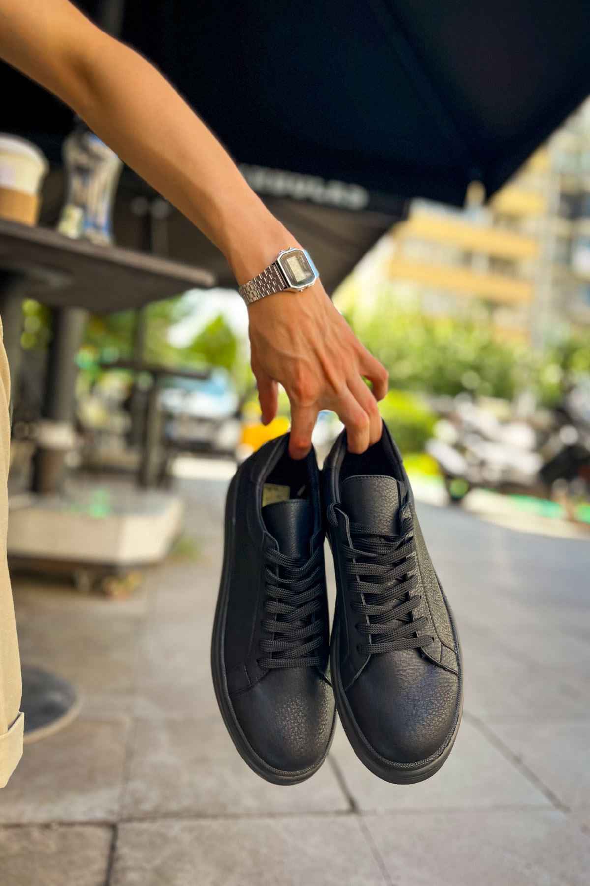 Black lace-up sneakers held together, textured upper with visible laces