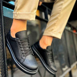 Black lace-up sneakers close-up, textured leather upper and white midsole trim