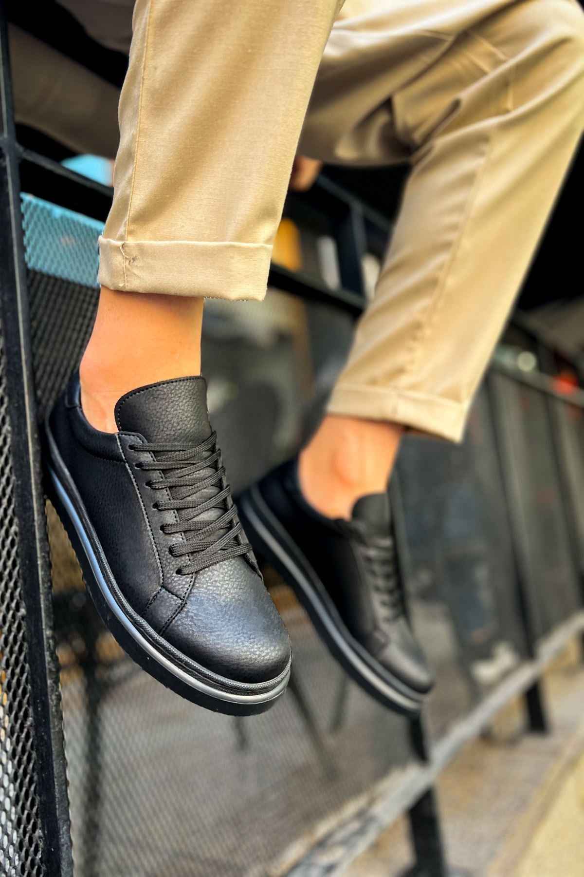 Black lace-up sneakers close-up, textured leather upper and white midsole trim