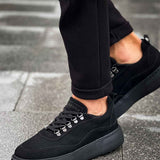 Black suede sneakers with low profile, silver eyelets, and rubber sole