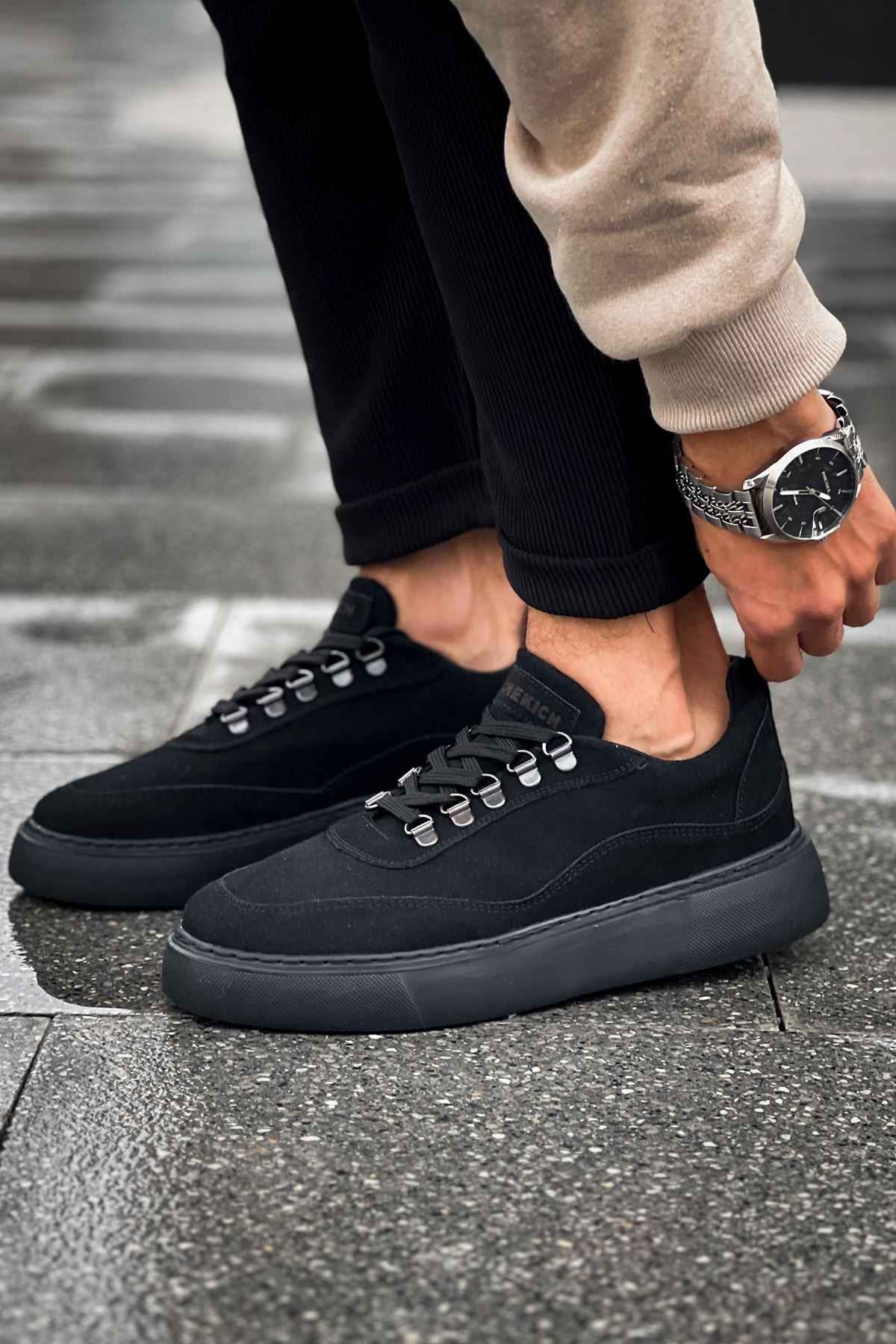 Black suede sneakers, side view with lace-up closure and cushioned sole