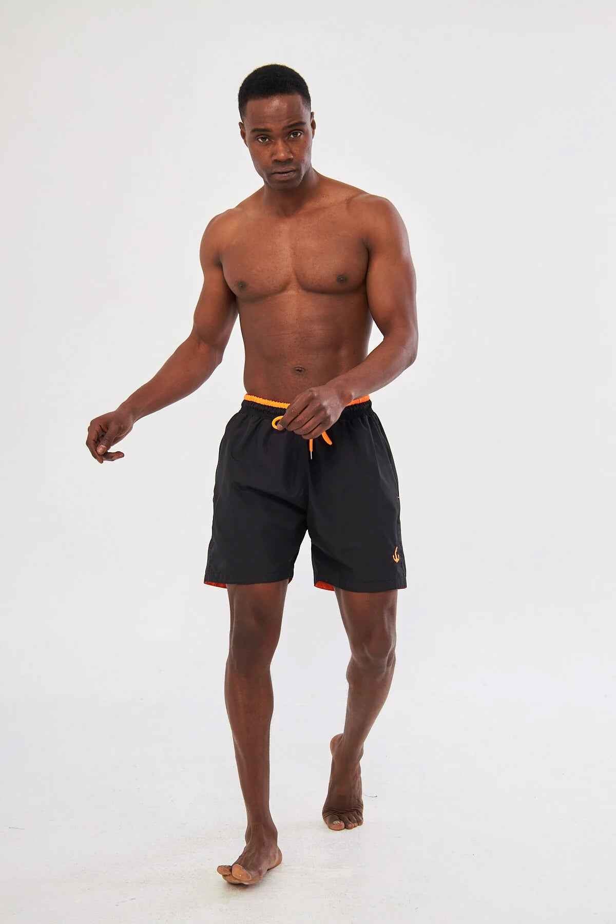 Men's black swim shorts with orange trim and drawstring, front view.