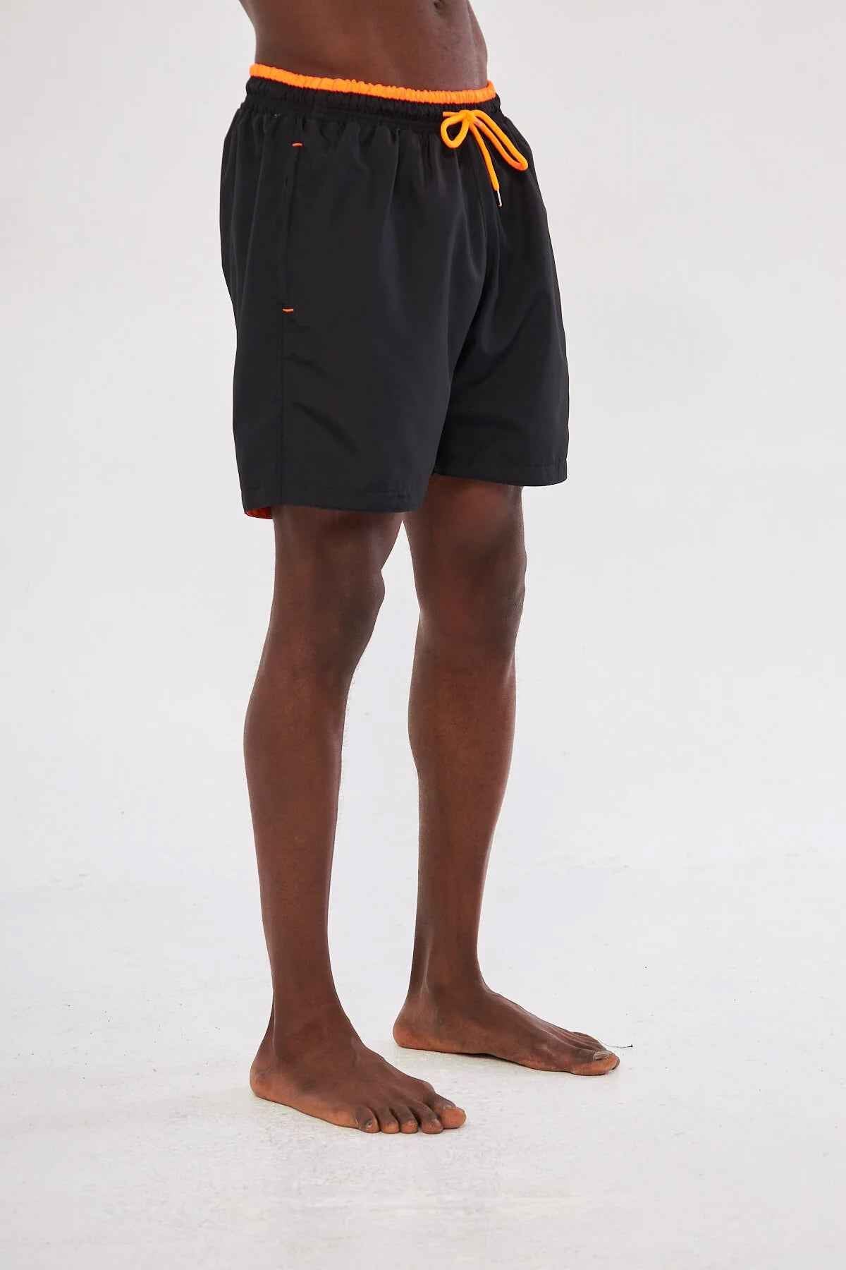 Men's black swim shorts, side view with orange drawstring and waistband trim.