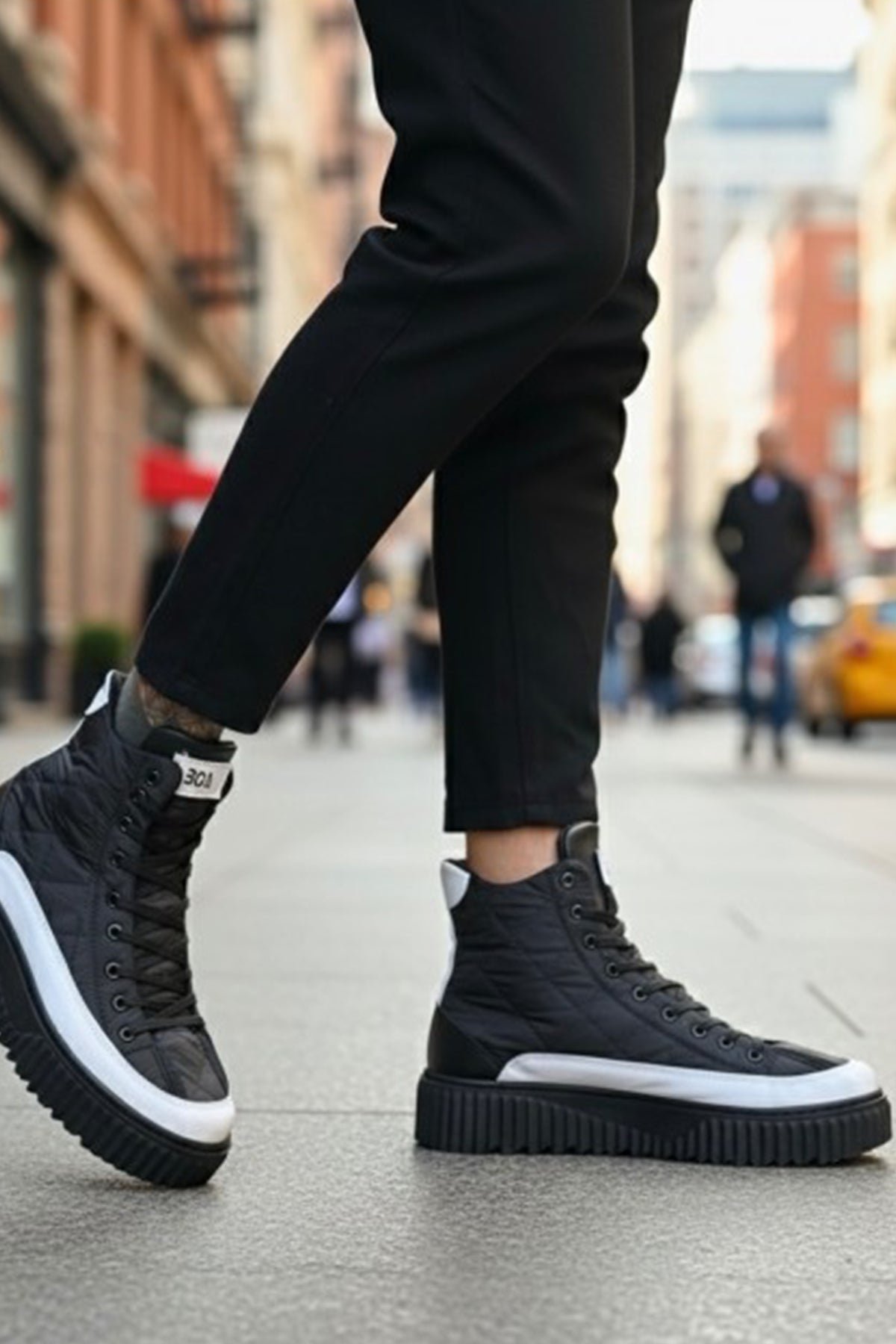 Black lace-up boots with white sole, worn with dark pants