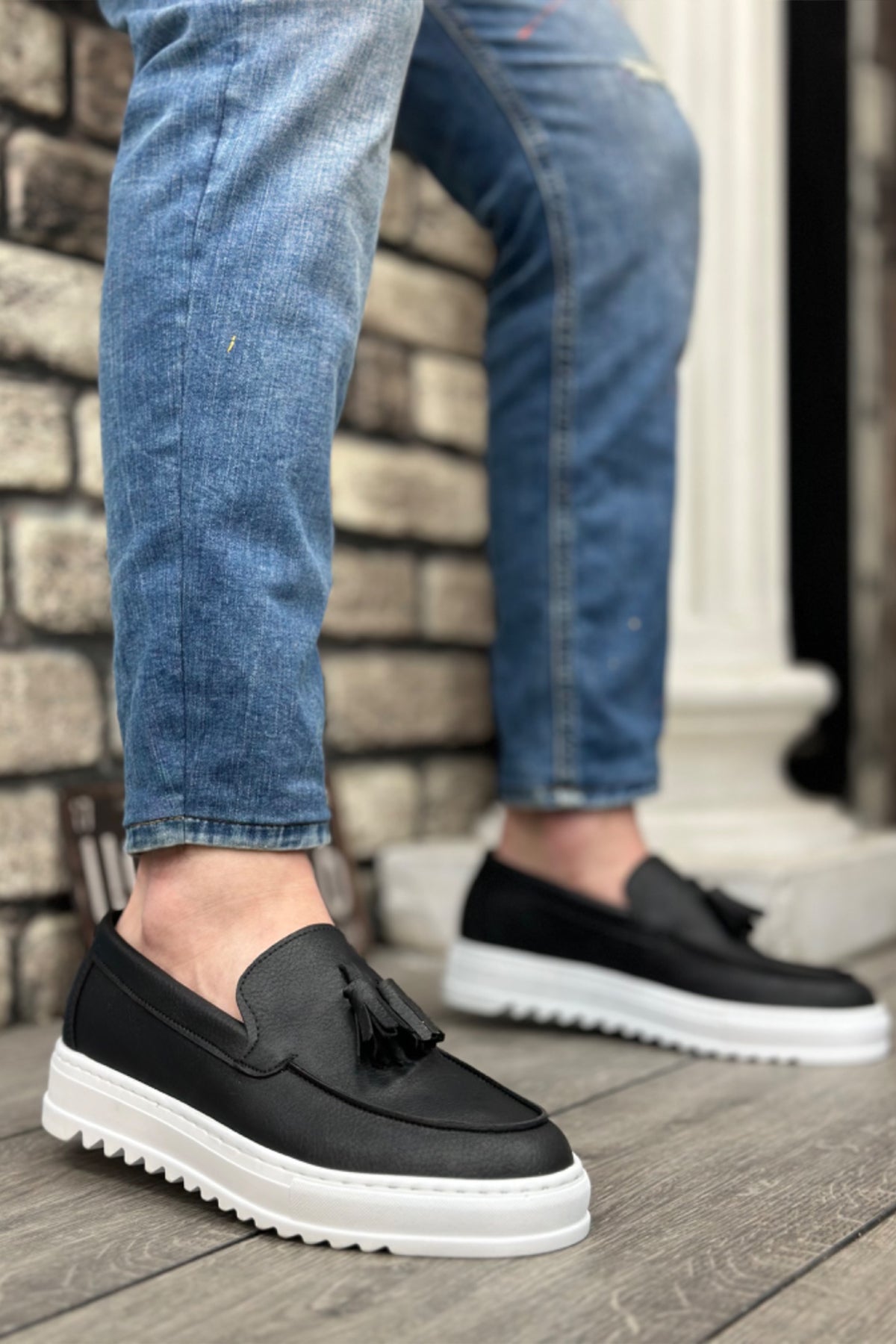 Black men's tassel loafer with slip-on design and white rubber sole