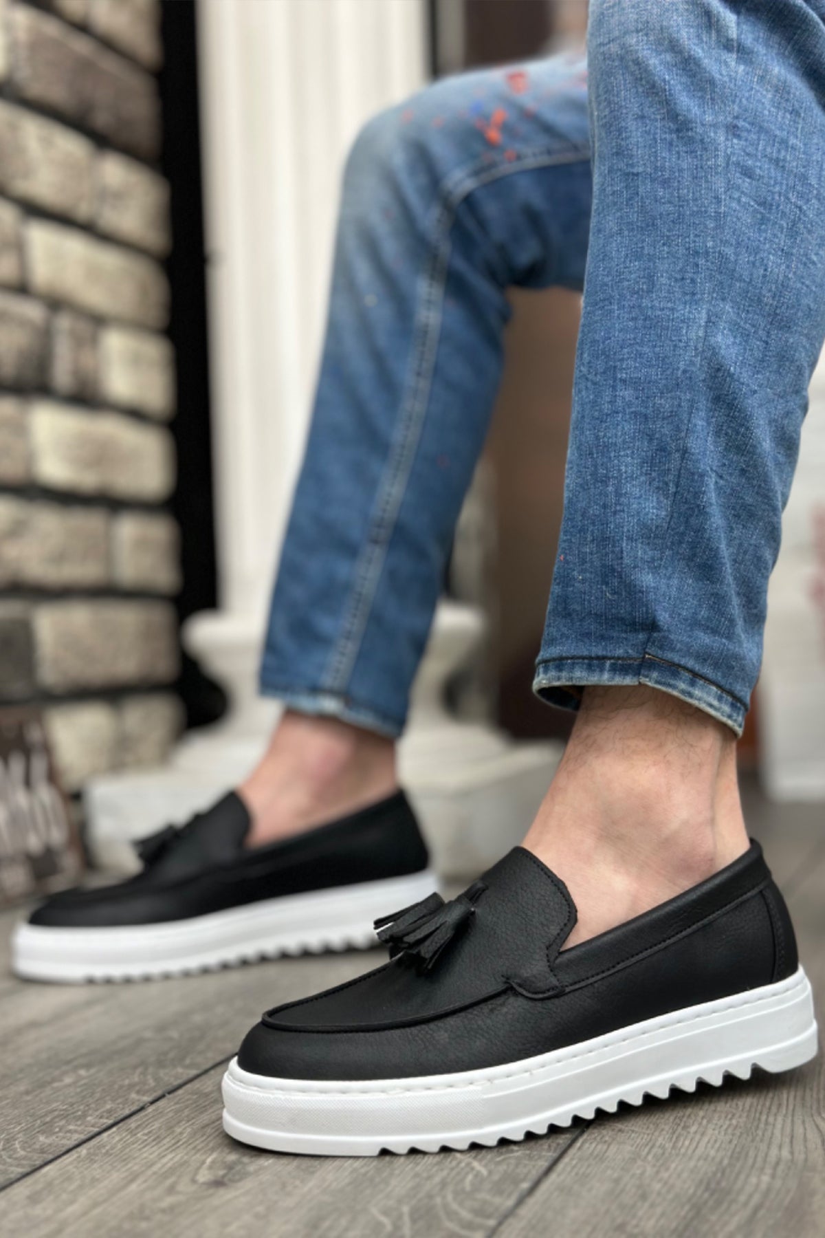 Black slip-on loafer with tassel detail and white cushioned sole