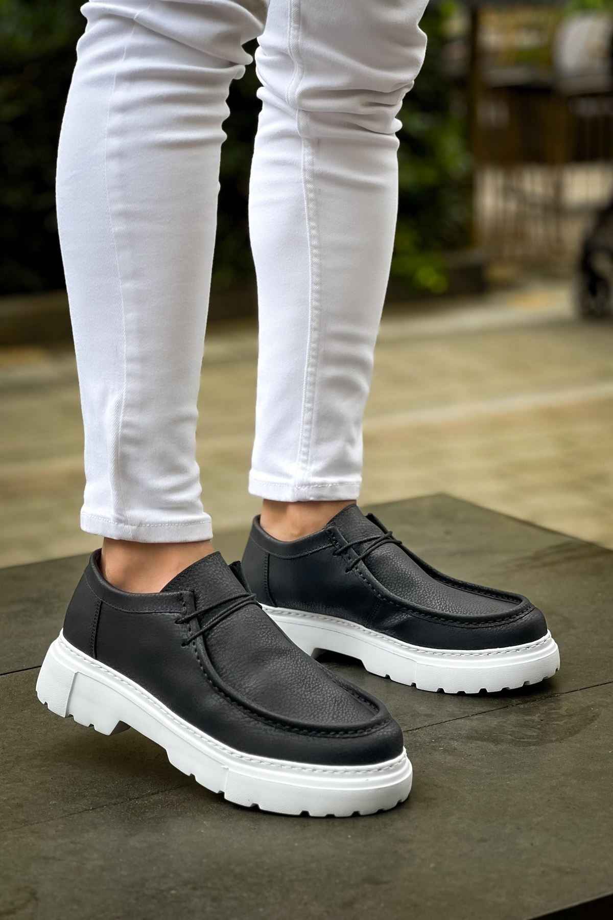 Men's black slip-on shoes with white chunky sole, textured upper and stitching
