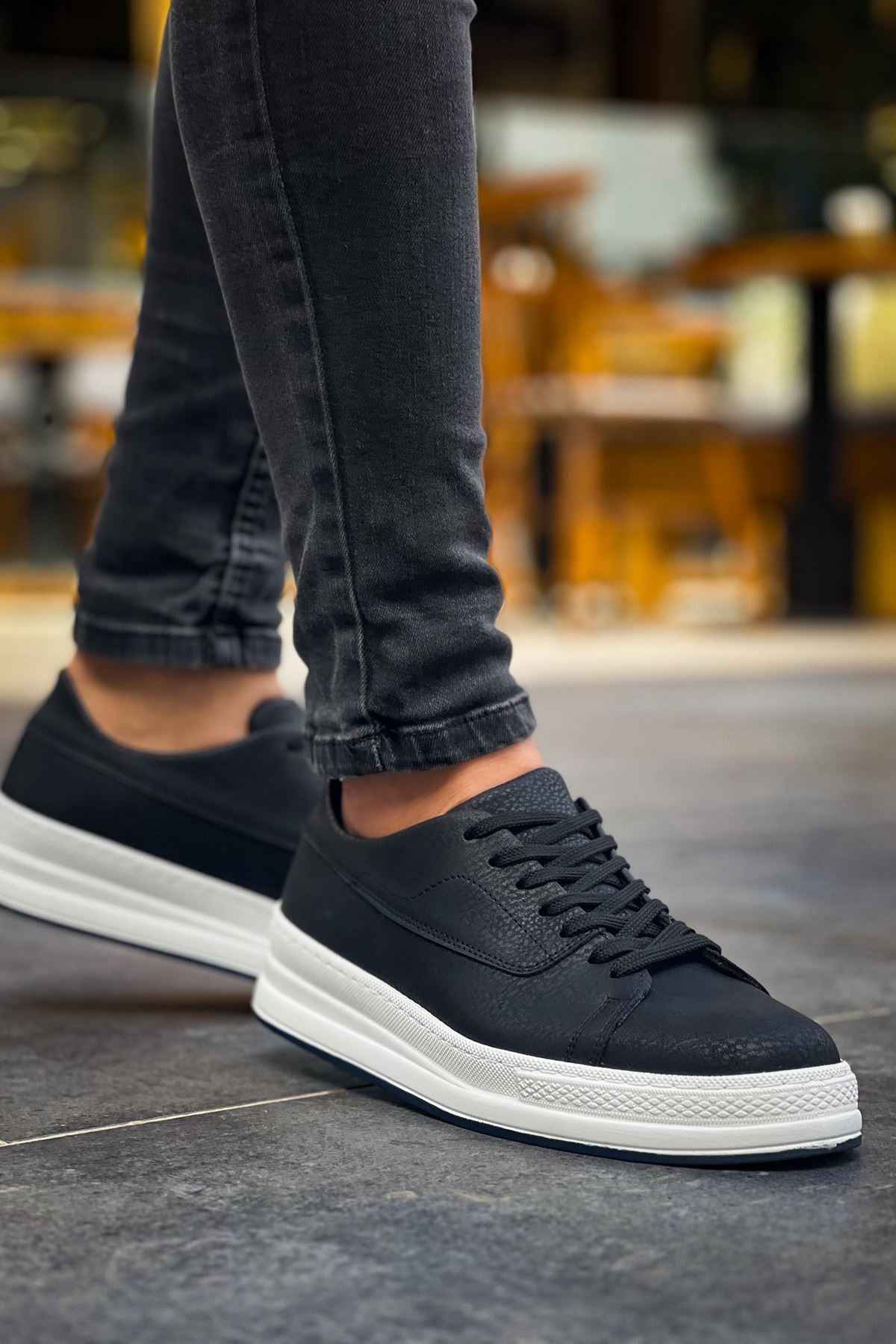 Black low-top lace-up sneakers with white rubber sole and textured upper