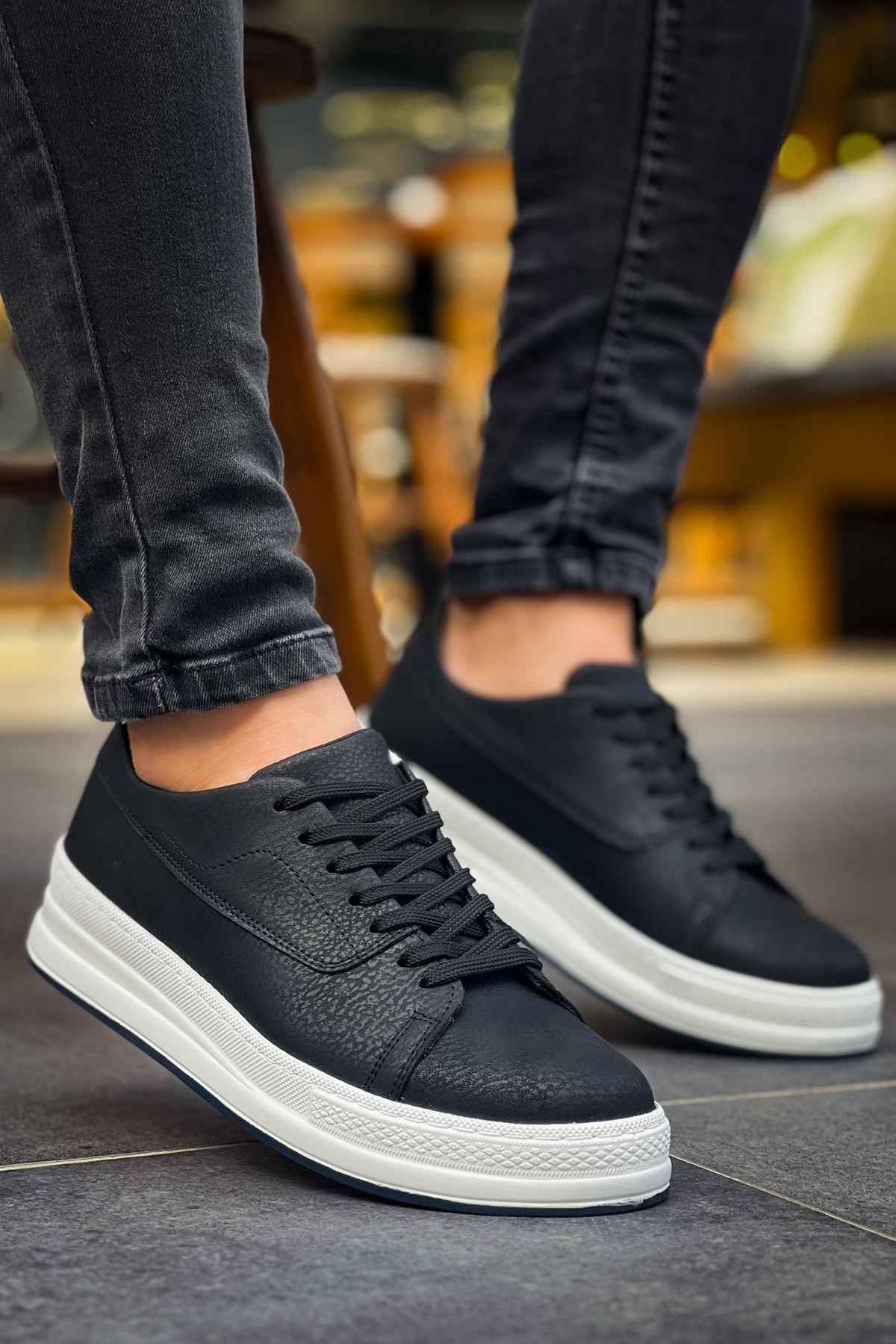 Black lace-up sneakers with white sole, side profile view