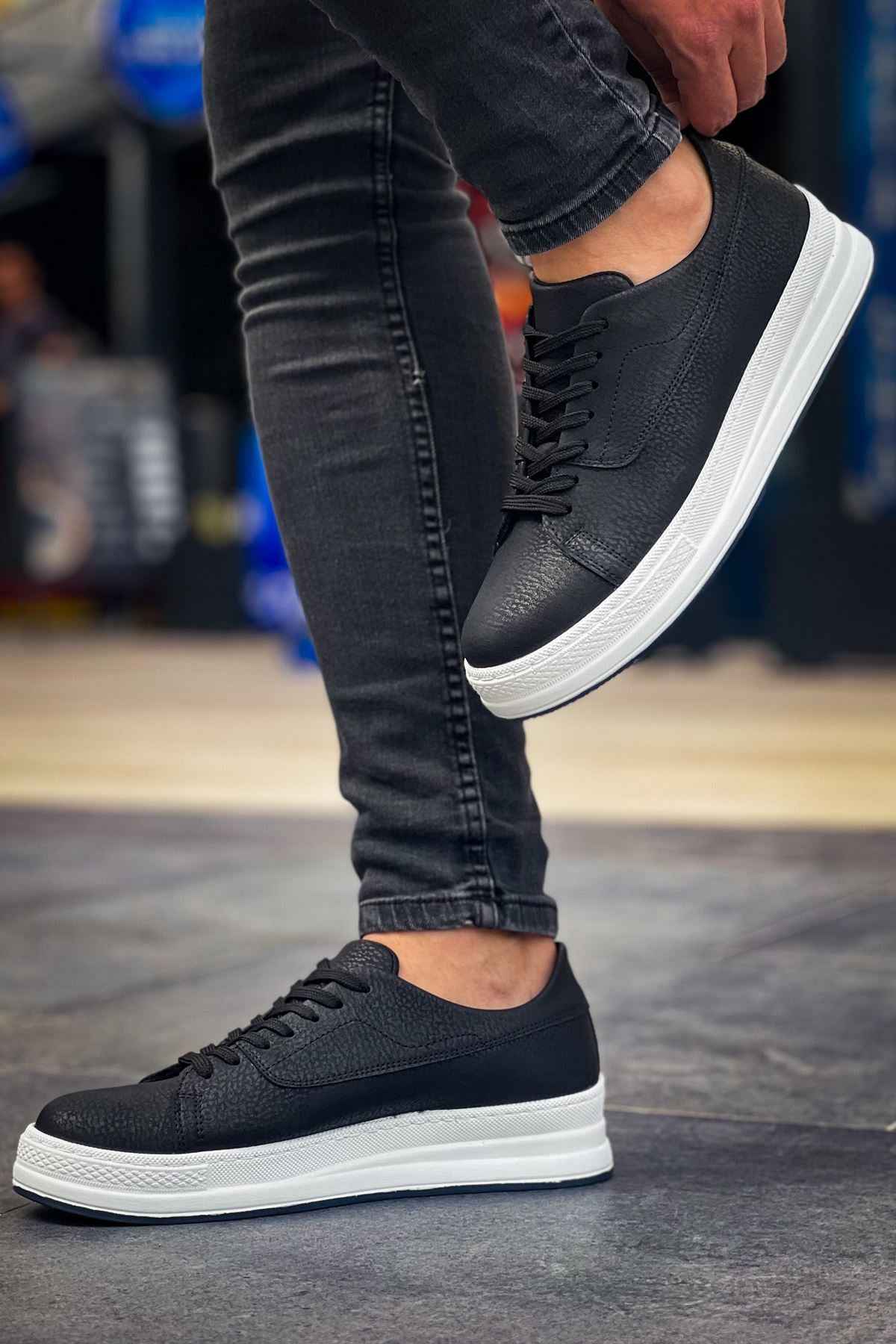 Black lace-up sneakers with white sole, front-and-side angle