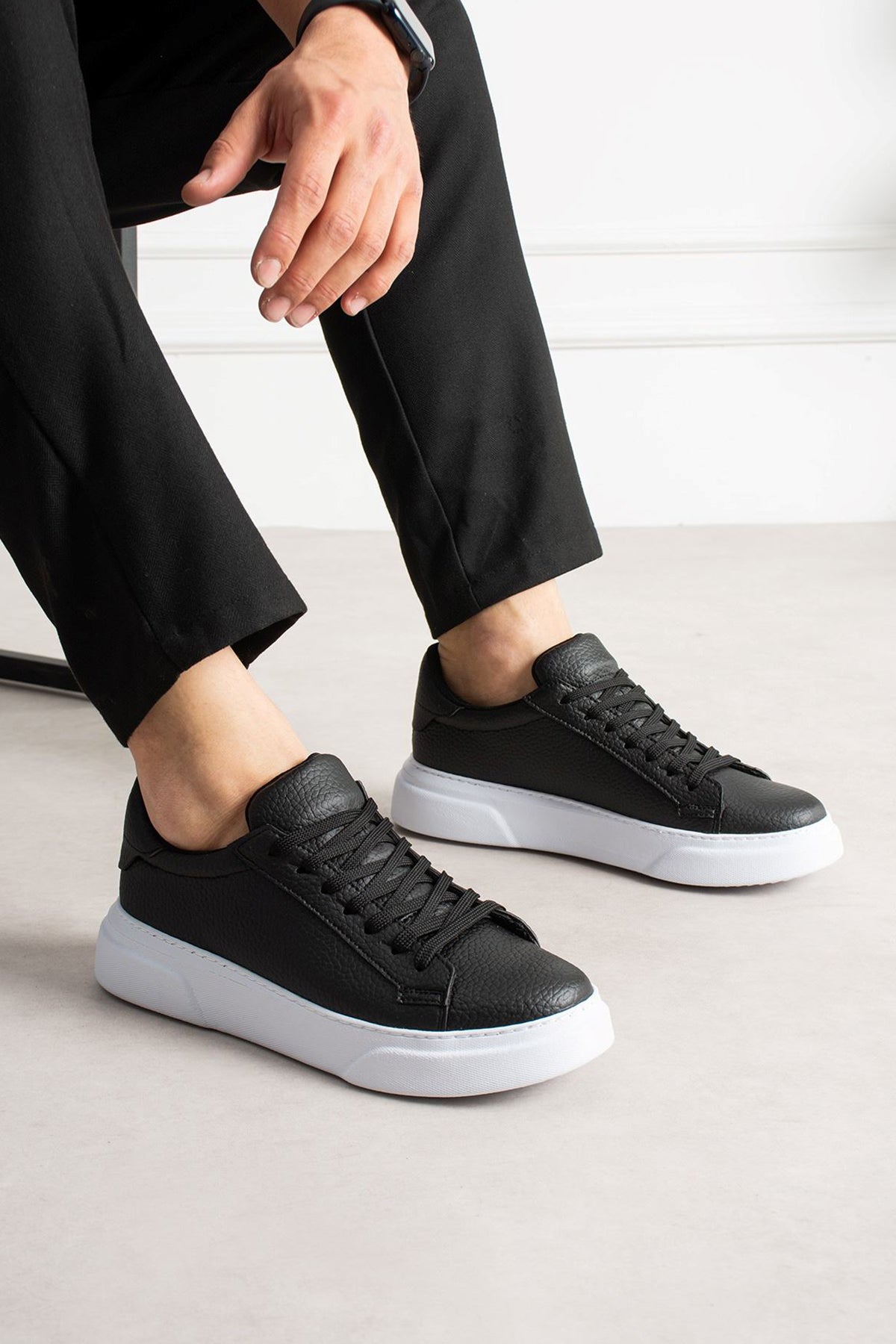 Black low-top sneakers with white rubber sole and lace-up design