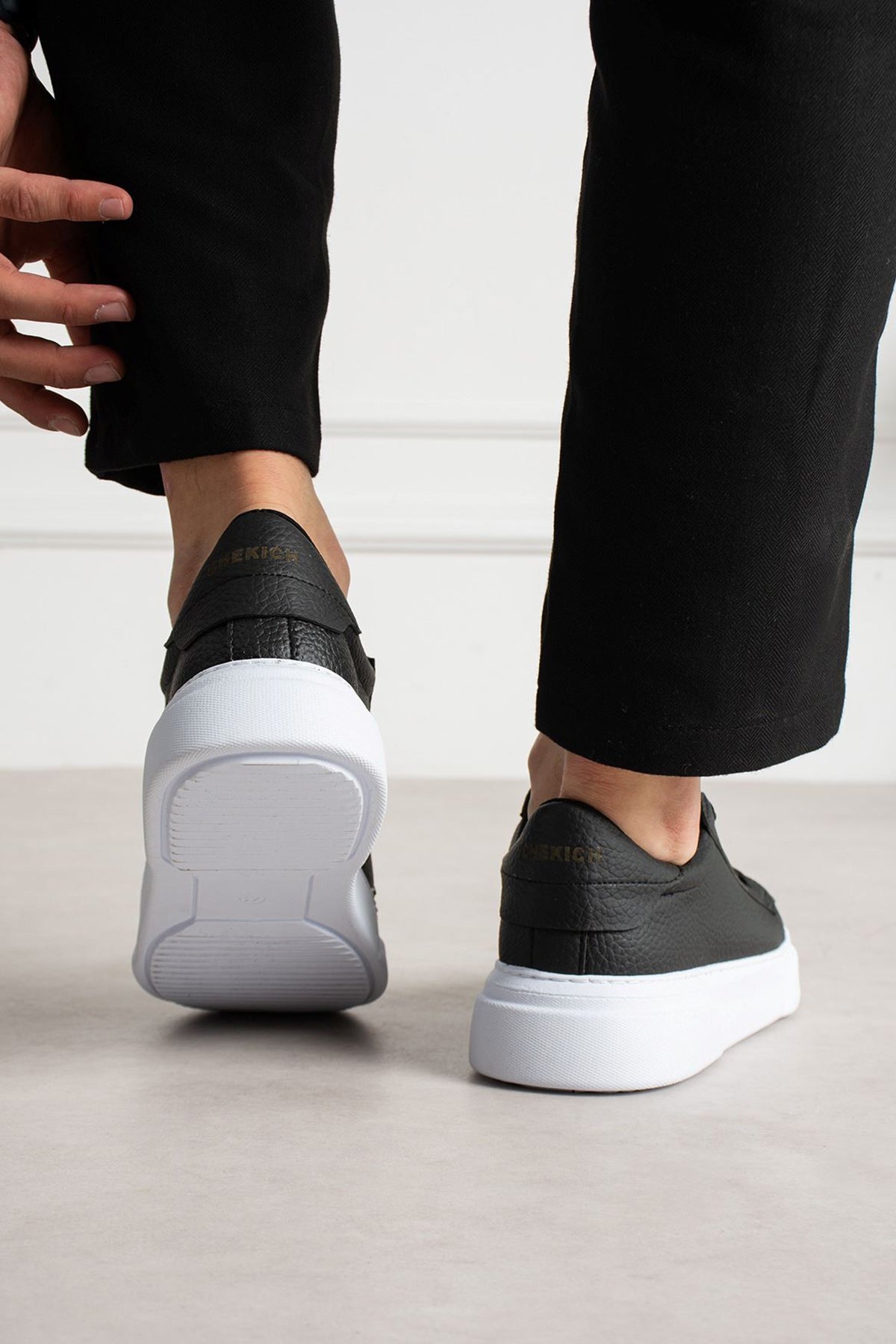 Black lace-up sneakers from heel view with white rubber sole