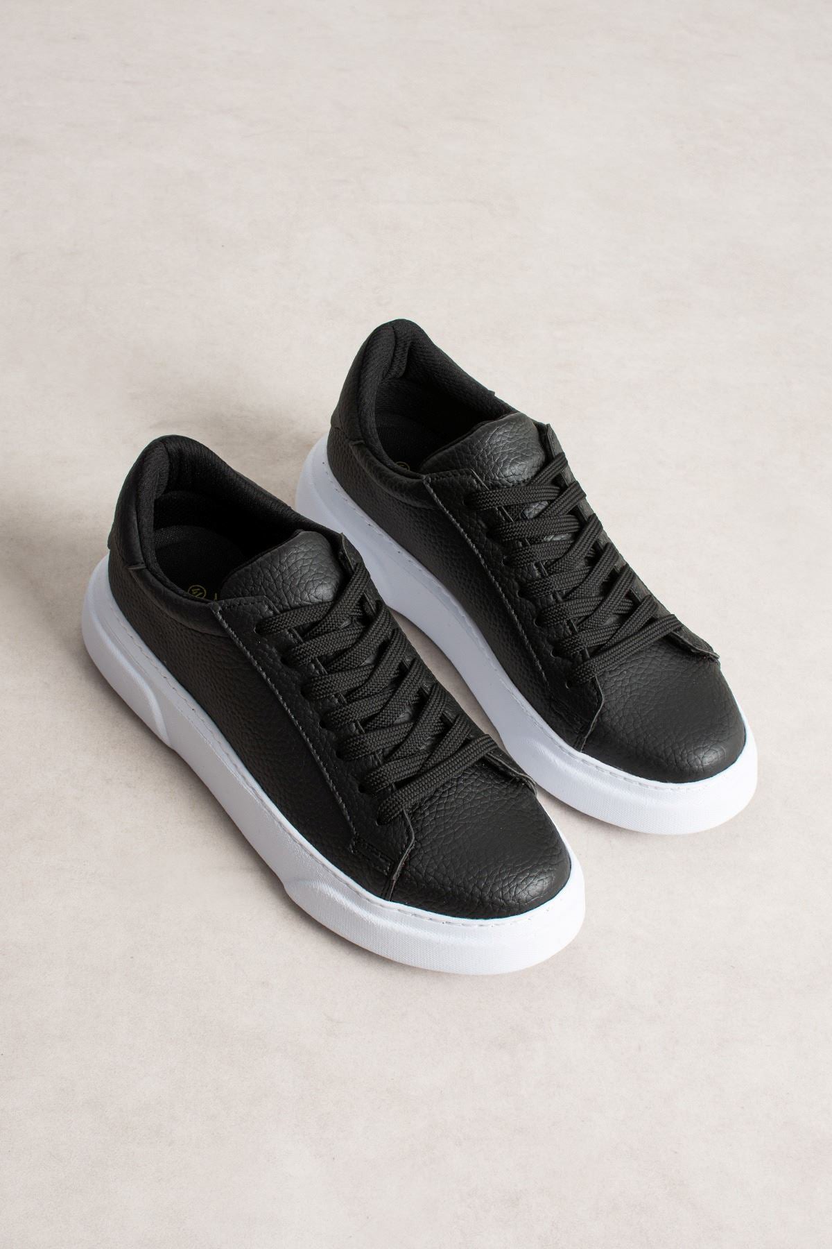 Pair of black leather-look lace-up sneakers with white platform soles