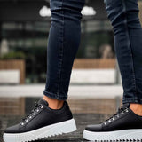 Men's black low-top sneakers with white outsole, lace-up eyelets, side stitching