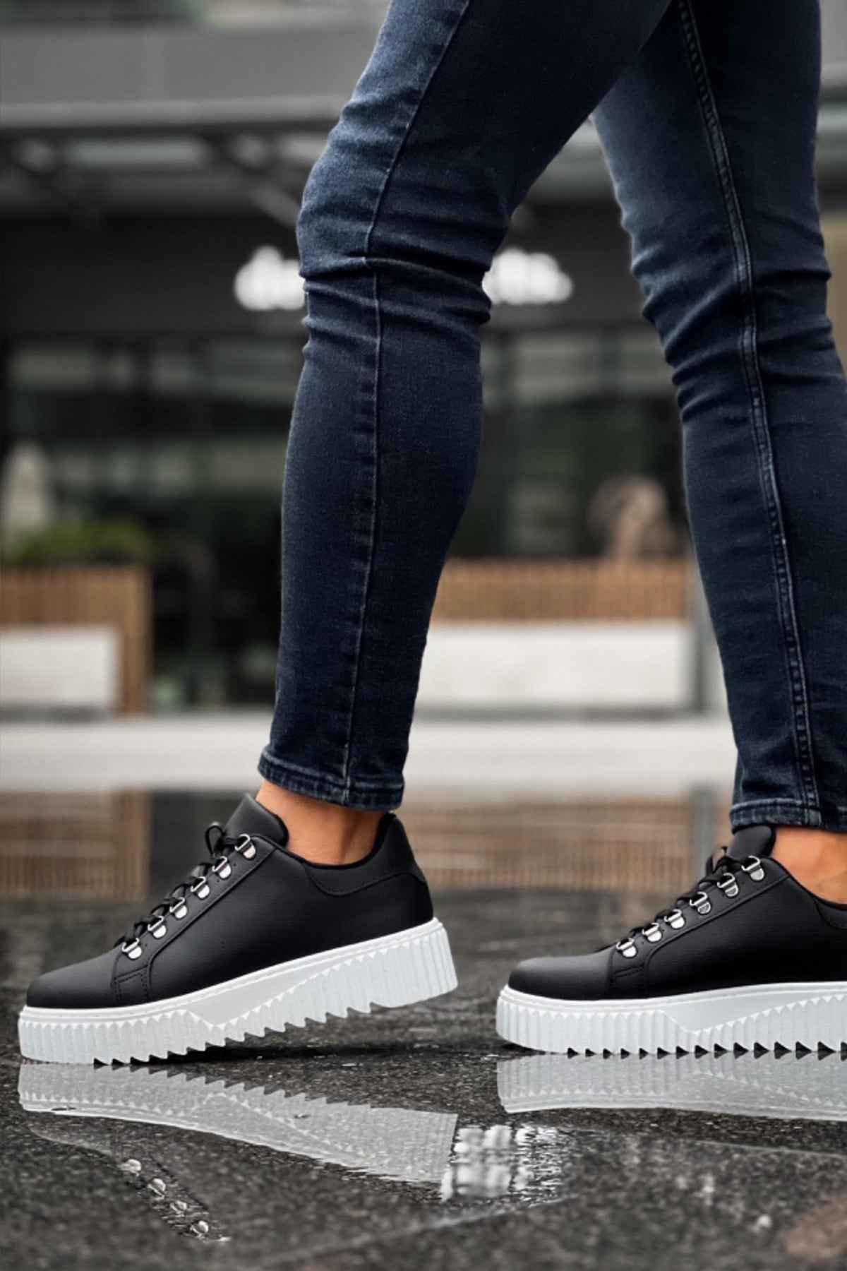 Men's black low-top sneakers with white outsole, lace-up eyelets, side stitching