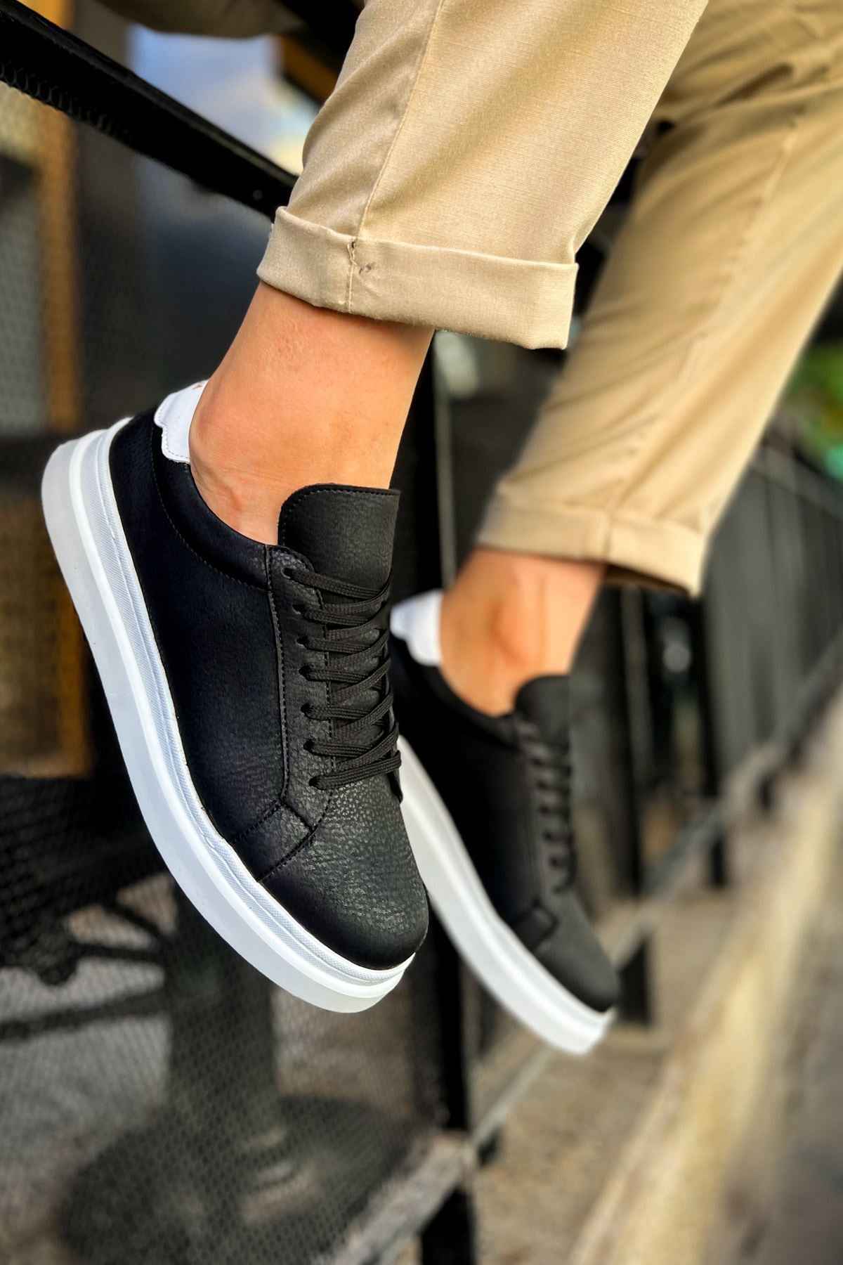 Men's black lace-up sneakers with white sole, shown in angled close-up