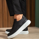 Black lace-up sneakers with white midsole, front-side angle