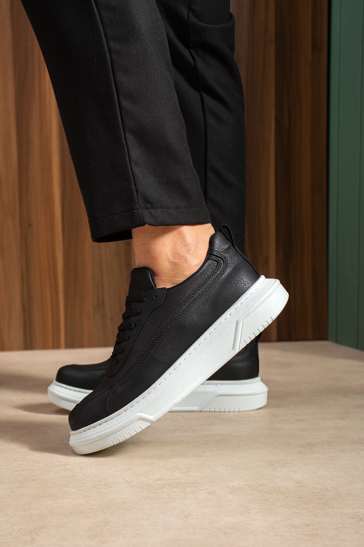 Black lace-up sneakers with white midsole, front-side angle