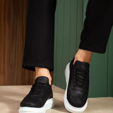 Black sneakers with white soles and laces, worn with cropped black pants