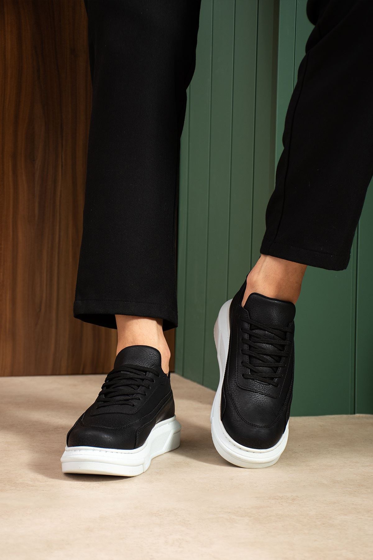 Black sneakers with white soles and laces, worn with cropped black pants