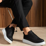 Black lace-up sneakers with white sole, profile view with bent leg