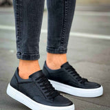 Black low-top sneakers with perforated toe, black laces, and white rubber sole