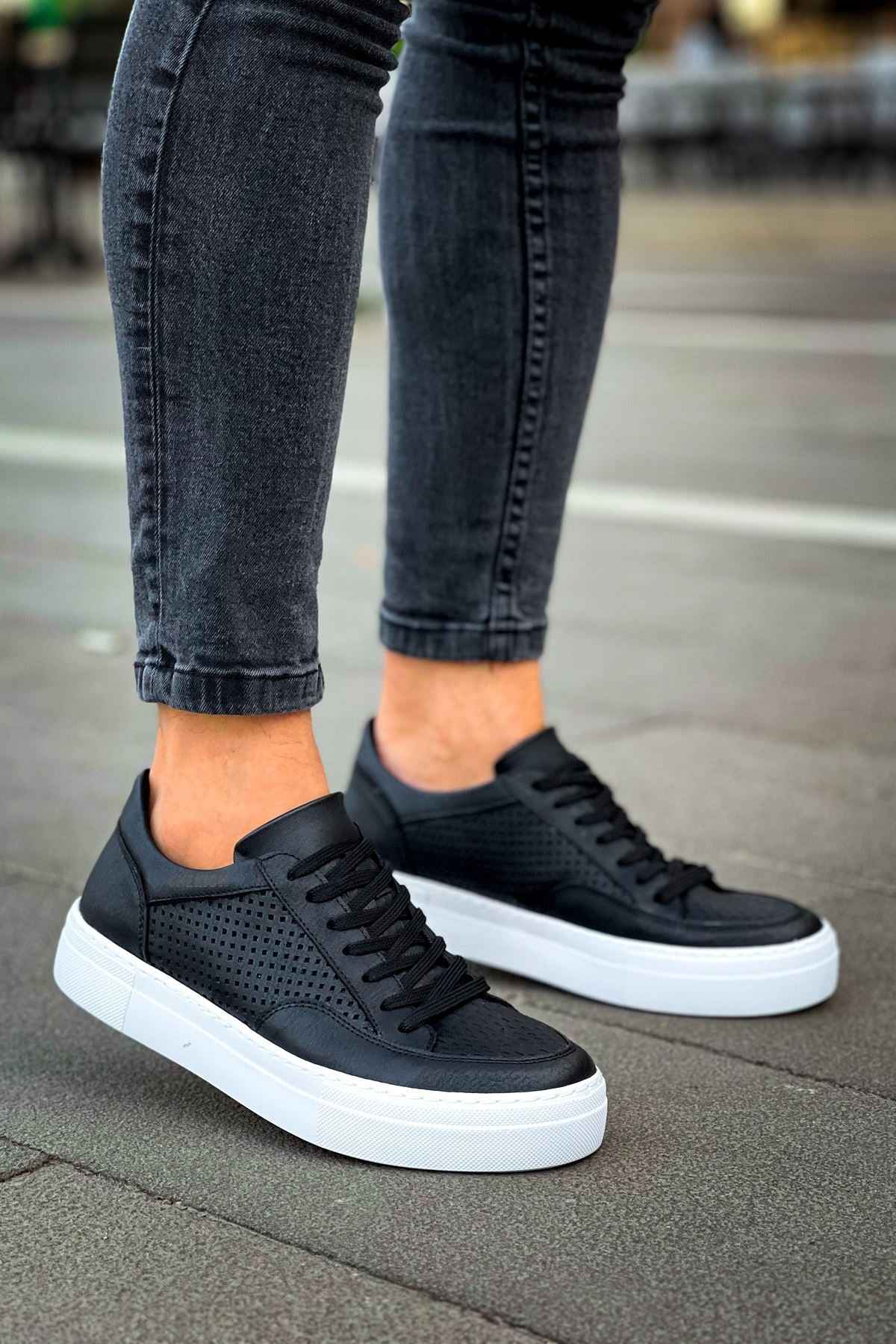 Black low-top sneakers with perforated toe, black laces, and white rubber sole