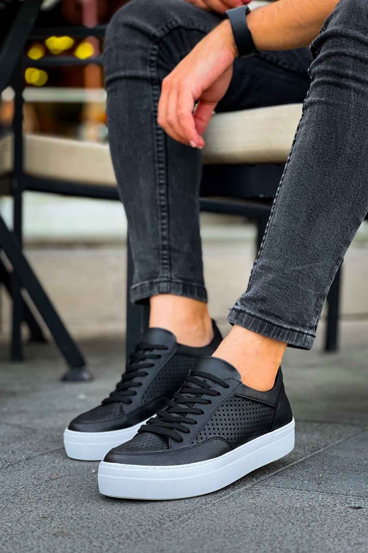 Black low-top sneakers with perforated panels, lace-up closure, and white cupsole