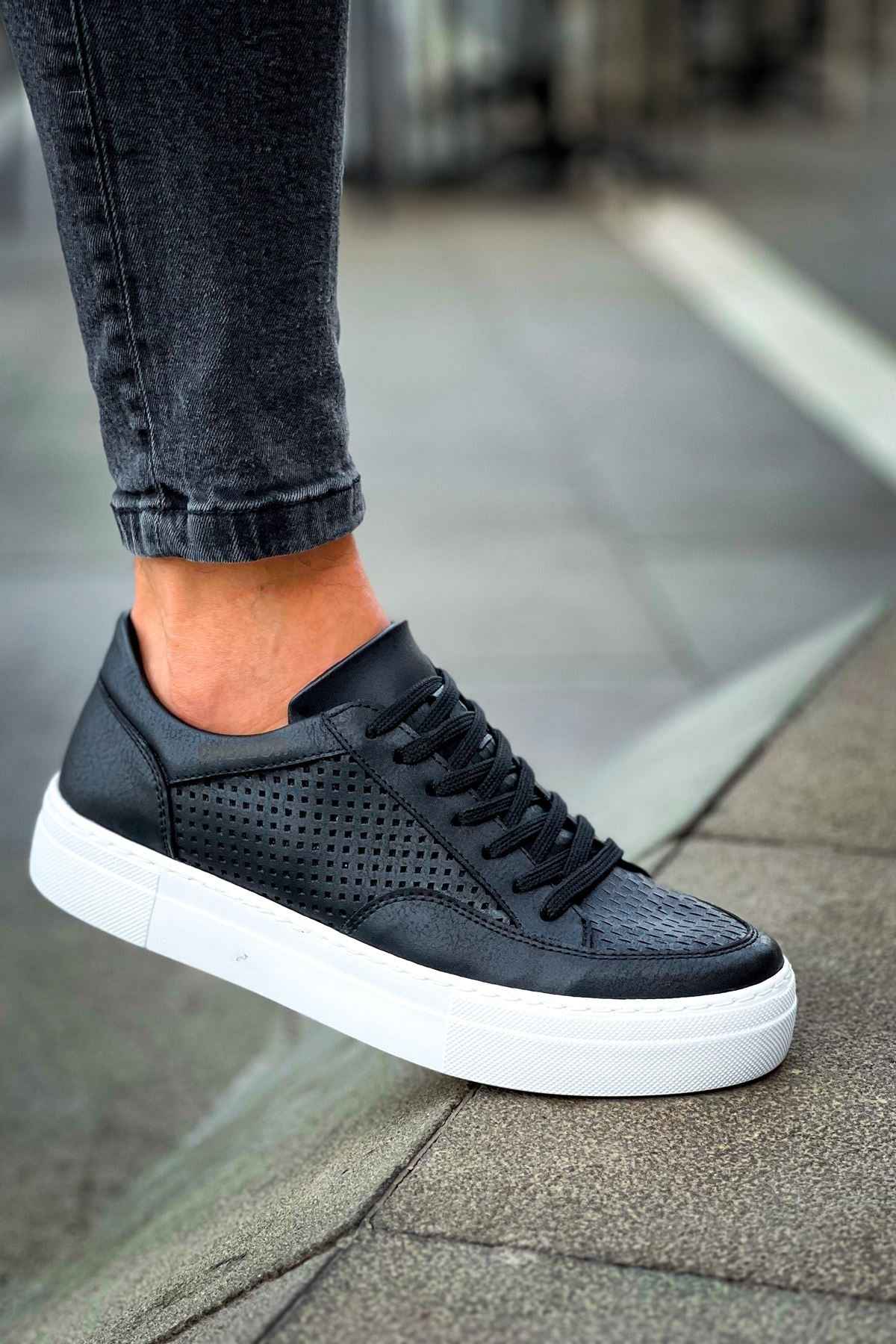 Black lace-up sneakers with perforated toe, black laces, and white rubber sole